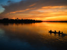 Barco com pessoas em crepúsculo no rio na região da Amazônia, onde serviço de internet será disponibilizado
