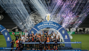 Foto frontal do palco de premiação do Campeonato Brasileiro de futebol feminino com as jogadoras do Corinthians celebrando