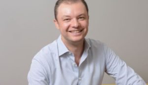 Emilio Puschmann, CEO da Amparo Saúde, olhando de frente sorrindo com camisa branca