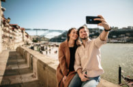 Casal de turistas tirando selfie na cidade do Porto, em Portugal, sem máscaras e sorrindo