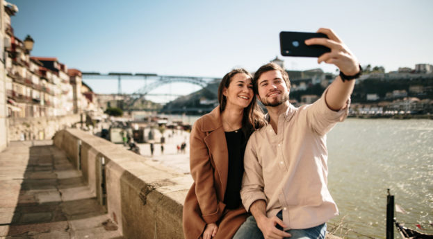 Casal de turistas tirando selfie na cidade do Porto, em Portugal, sem máscaras e sorrindo