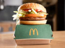 Hambúrguer vegetal McPlant, do McDonald's, sobre caixa na cor verde e logo da rede
