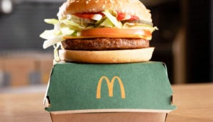 Hambúrguer vegetal McPlant, do McDonald's, sobre caixa na cor verde e logo da rede