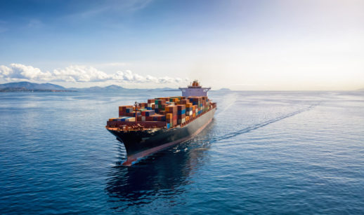 Navio cargueiro com muitos contêineres em meio ao mar azul, alusivo ao transporte sustentável pretendido por Amazon e outras gigantes