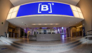 Interior da B3, com painel azul luminoso e foco no logo da empresa