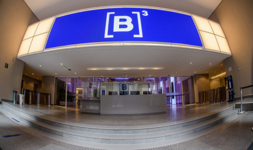 Interior da B3, com painel azul luminoso e foco no logo da empresa