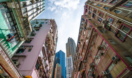 Perspectiva de baixo para cima de prédios residenciais pobres na China e, ao fundo, prédios modernos comerciais, alusivo às desigualdades do país