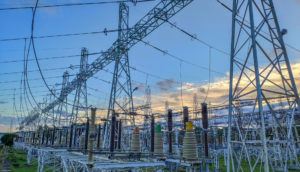 Torre de transmissão de energia vista de baixo para cima com raio solar passando pelas estruturas, alusivo a Energias do Brasil (ENBR3)