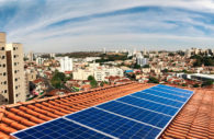 Painel de energia solar sobre telhado de casa com cidade ao fundo