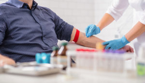 Profissional de laboratório recolhendo sangue de paciente, alusivo às atividades do Grupo Fleury (FLRY3)