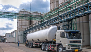 Imagem de caminhão e tanques de combustíveis ao fundo, alusivo à base de distribuição de Raízen, Ipiranga e Vibra Energia