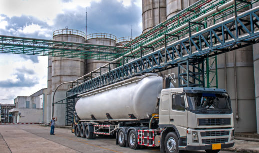 Imagem de caminhão e tanques de combustíveis ao fundo, alusivo à base de distribuição de Raízen, Ipiranga e Vibra Energia