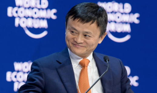 Jack Ma, fundador do Alibaba, sorrindo de terno azul e gravata laranja com backdrop atrás com logos do World Economic Forum