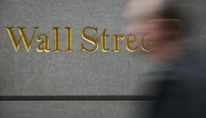 Foto de parede com destaque para Wall Street e pessoa passando em frente borrada, alusivo à carteira Safra Top 10 BDRs