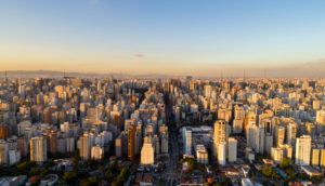 Foto aérea de prédios de São Paulo em meio ao pôr do sol, alusivo ao setor imobiliário