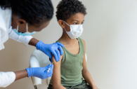 Enfermeira aplicando vacina em criança, alusivo à vacinação contra a malária