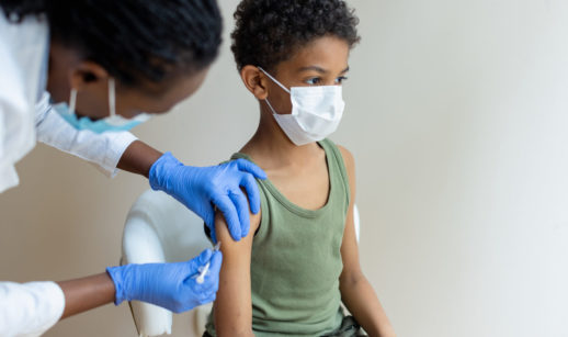 Enfermeira aplicando vacina em criança, alusivo à vacinação contra a malária