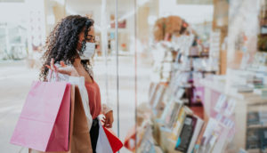 Mulher com sacolas olhando a vitrine em shopping, alusivo às vendas do varejo