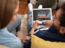 Homem e mulher sentados em sofá com o laptop e cartão de crédito em mãos prontos para comprar na Black Friday