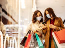 Duas mulheres de máscara e com sacolas nas mãos fazendo compras em shoppings com a Black Friday