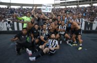 Atletas do Botafogo reunidos em frente à arquibancada com a torcida ao fundo