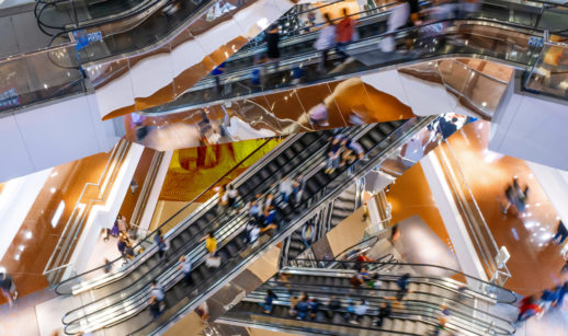Escadas rolantes de shoppings com pessoas andando, alusivo às vendas