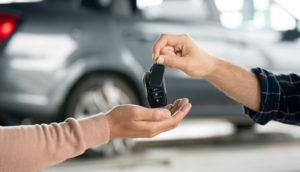 Close de mãos de pessoas trocando chaves de carro, alusivo às vendas de veículos