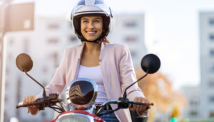 Mulher sorrindo de capacete em cima de motocicleta, alusivo às vendas de motos no Brasil em novembro
