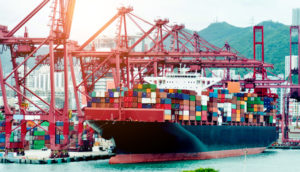 Imagem de frontal de navio cargueiro sendo abastecido por ponte rolante em porto, alusivo ás exportações da China em novembro
