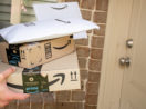 Mãos de pessoa segurando três pacotes da Amazon, alusivo a compras feitas com cupons de descontos