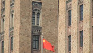 Bandeira da China em frente a prédios de estilo europeu, alusivo às empresas de tecnologia