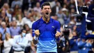 Novak Djokovic, que teve o visto cancelado na Austrália, gritando com os punhos cerrados de camisa azul durante jogo de tênis