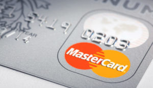 Detalhe de cartão de crédito Platinum da Mastercard, com destaque para o logo laranja e amarelo da empresa