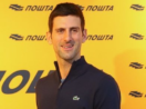Novak Djokovic sorrindo com suéter azul e fundo amarelo