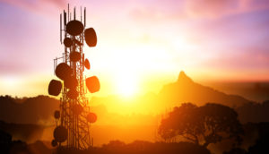 Paisagem do pôr do sol com silhueta de torre de telefonia móvel, alusivo à venda de ativos da Oi