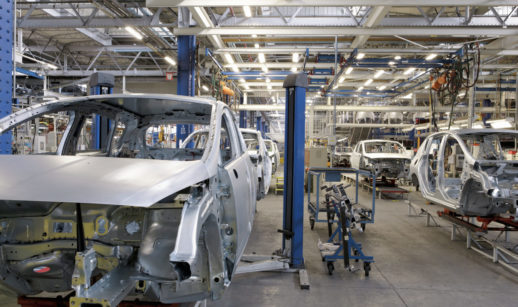 Linha de produção de veículos com carrocerias em linha de fábrica e maquinário no entorno