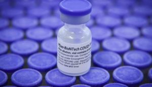 Detalhe de dose da vacina da Pfizer contra a covid-19, com frasco branco e tampa roxa