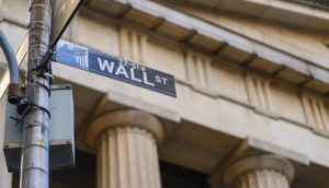 Detalhe de placa de Wall Street com a NYSE de fundo, alusivo aos BDrs para investir em fevereiro