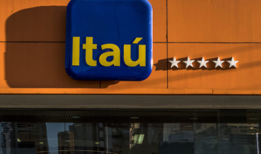 Fachada do Itaú em laranja, com destaque com placa com o logo da empresa em azul