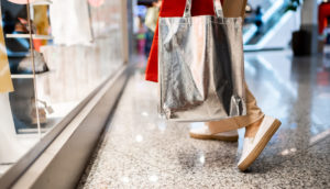 Close de pessoa andando em shopping center com sacolas de compras, alusivo às atividades da Multiplan