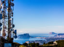 Torre de telecomunicações à esquerda, em cima de morro, com vista para cidade ao fundo, alusivo à venda de ativos da Oi para a TIM Brasil
