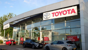 Fachada de concessionária da Toyota com carros na frente pela manhã