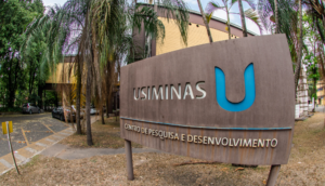 Entrada de unidade administrativa da Usiminas, com placa na frente com logo da empresa e o "U" em azul