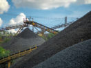 Montanhas de minério de ferro com máquinas amarelas trabalhando, alusivo à produção da Vale