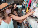 Duas mulheres lado a lado escolhendo roupas em arara de loja, alusivo às vendas do varejo brasileiro