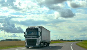 Caminhão na cor branca, da Volvo, andando por estrada com céu azul pouco nublado, alusivo aos investimentos no Brasil