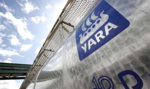 Perspectiva de baixo para cima de prédio transparente da Yara, com destaque par ao logo da empresa estampado em azul e branco