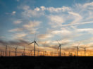 Parque de energia eólica em pôr do sol, com silhuetas das hélices dos geradores, alusivo ao novo empreendimento da BRF e da AES Brasil no Nordeste
