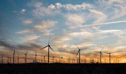 Parque de energia eólica em pôr do sol, com silhuetas das hélices dos geradores, alusivo ao novo empreendimento da BRF e da AES Brasil no Nordeste