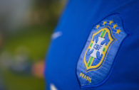Detalhe da camisa azul da seleção brasileira, com close no escudo da CBF, alusivo aos clubes brasileiros de futebol, que tiveram lucro nos últimos 5 anos